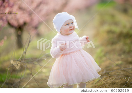 Little princess Toddler dressed in a pink dress walks in the fresh air and enjoys life. 60202919