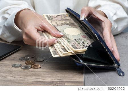 Close up female hand holding Japanese yen 10000 banknotes 60204922
