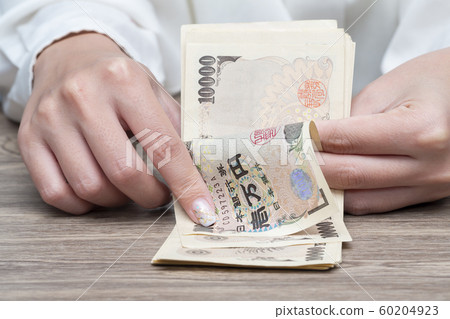 Close up female hand counting Japanese yen bank notes 60204923