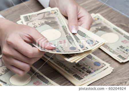 Close up female hand counting Japanese yen bank notes 60204924