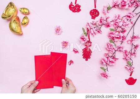 Flat lay Chinese lunar new year hand offering red envelope on pink background Flat lay Chinese lunar new year hand offering red envelope on pink background 60205150