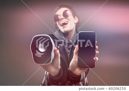Caucasian girl with rough facial features in a black jacket listen to music with phone and little Caucasian girl with rough facial features in a black jacket listen to music with phone and little 60206250