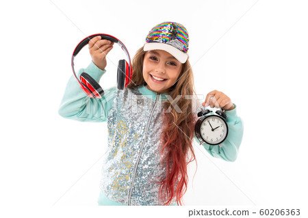 Little pretty caucasian girl in a tracksuit with big earphones and alrm clock, picture isolated on Little pretty caucasian girl in a tracksuit with big earphones and alrm clock, picture isolated on 60206363