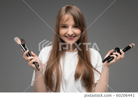 Caucasian teenager do makeup with brushes isolated on grey background Caucasian teenager do makeup with brushes isolated on grey background 60206441