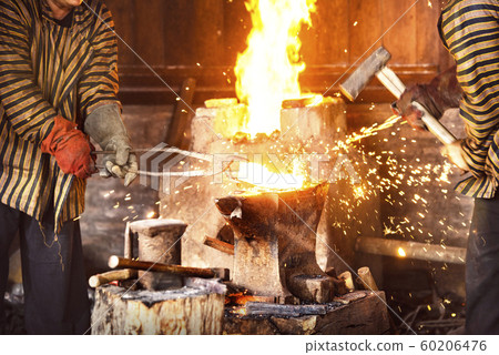Blacksmith forging the molten metal with a hammer Blacksmith forging the molten metal with a hammer 60206476