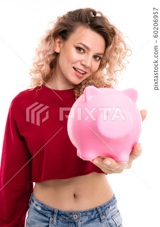 European attractive girl holds a piggy bank in hands on a white studio wall, 60206957