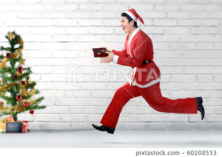 Asian man in Santa costume running while holding the gift box Asian man in Santa costume running while holding the gift box 60208553
