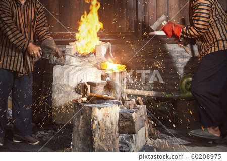 Blacksmith forging the molten metal with a hammer 60208975