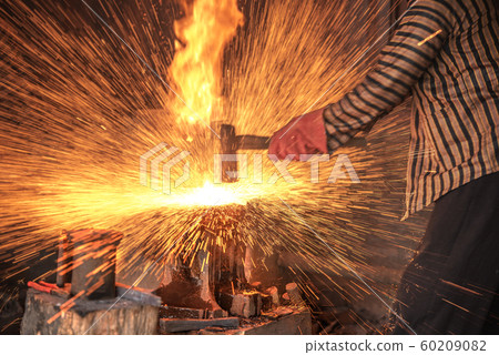 Blacksmith forging the molten metal with a hammer Blacksmith forging the molten metal with a hammer 60209082