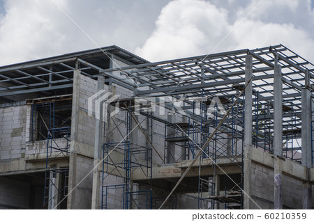 Building and Construction Site in progress. Building construction site against cloudy sky. Metal construction of unfinished building on construction of multi storage building. 60210359