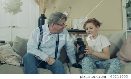 Teenage boy is showing VR-glasses to his grandfather 60211993