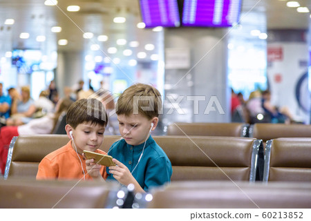 Two little boy sitting in an airport departure Two little boy sitting in an airport departure 60213852