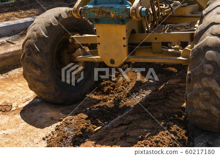 Details of grader is working on road construction. Grader industrial machine on construction of new roads. Heavy duty machinery working on highway. Construction equipment. Compaction of the road. Details of grader is working on road construction. Grader industrial machine on construction of new roads. Heavy duty machinery working on highway. Construction equipment. Compaction of the road. 60217180