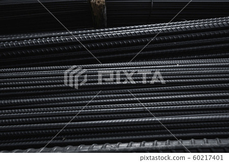 Building armature in the warehouse of metallurgical products or on construction site. Stack of heavy metal reinforcement bars with periodic profile texture. Steel construction armature. Building armature in the warehouse of metallurgical products or on construction site. Stack of heavy metal reinforcement bars with periodic profile texture. Steel construction armature. 60217401