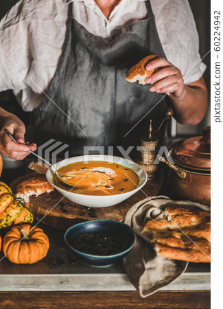 Woman in grey apron mixing cream with pumpkin 60224942