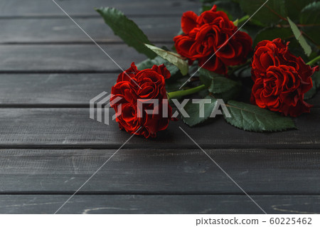Red roses flowers over black wooden background 60225462