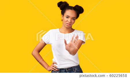 Young black woman showing stop sign over yellow background Young black woman showing stop sign over yellow background 60225658