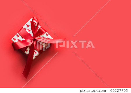 Christmas giftbox with red ribbon on red surface. 60227705