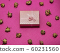 Photo flat lay gift box with bow among dried rose buds on a pink background top view 60231560