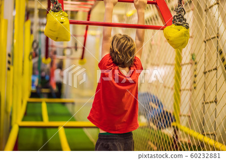 Portrait of 6 years old boy wearing helmet and climbing. Child in abstacle course in adventure Portrait of 6 years old boy wearing helmet and climbing. Child in abstacle course in adventure 60232881