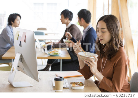 Working woman business scene eating in front of a PC Working woman business scene eating in front of a PC 60235737