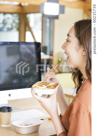 Working woman business scene eating in front of a PC Working woman business scene eating in front of a PC 60235739