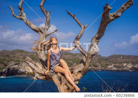 Woman sitting on a tree against the background of the sea Angel's Billabong in Nusa Penida, Bali 60236666