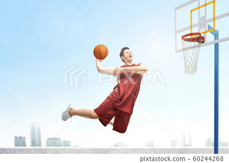 Asian basketball player man jumps in the air with the ball Asian basketball player man jumps in the air with the ball 60244268