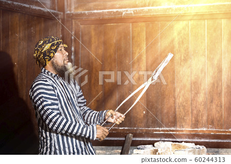 Asian blacksmith holding the molten metal with pliers 60244313