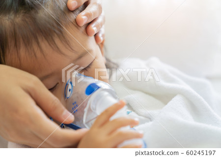 Asian baby girl breathing treatment with mother Asian baby girl breathing treatment with mother 60245197