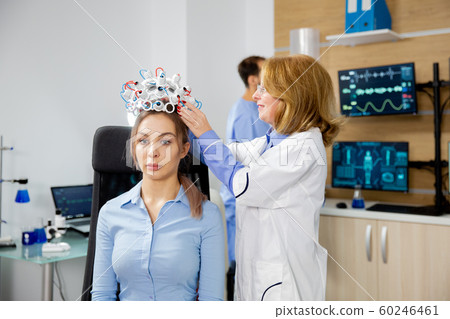 Female scientist who puts brain waves scanning device on a female patient Female scientist who puts brain waves scanning device on a female patient 60246461