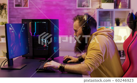 Professional game player wearing headphones in a room with colorful neons 60246923