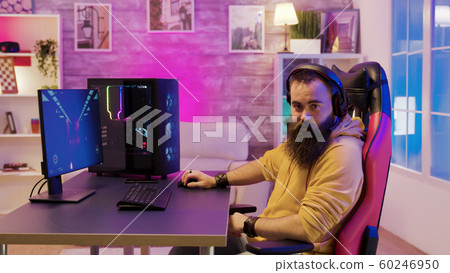 Man sitting on a gaming chair and playing video games in his room 60246950