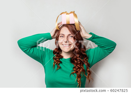 Young cute curly girl in a green sweater and holds 60247825
