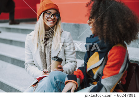 Young Caucasian and Afro American women together outdoors Young Caucasian and Afro American women together outdoors 60247891
