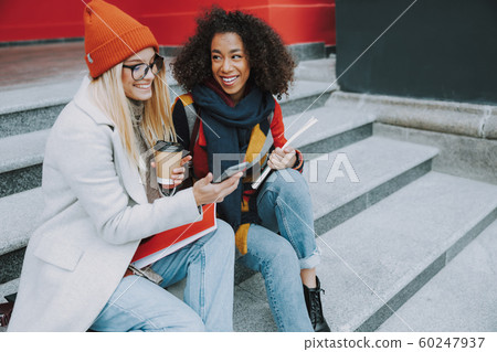 Young Caucasian and Afro American women sitting together 60247937
