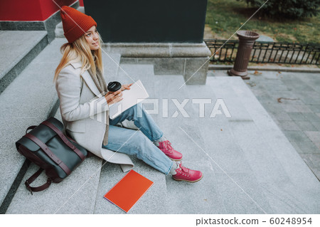 Pretty woman with copybooks and coffee outdoors 60248954