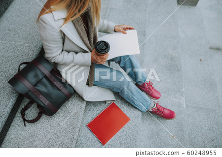 Female student with copybooks sitting on stairs Female student with copybooks sitting on stairs 60248955