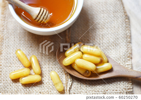 Royal jelly capsules in wooden spoon on sack 60250270