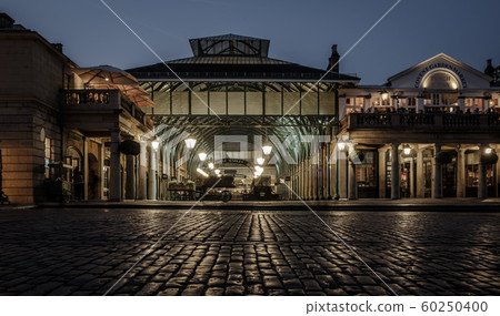 Covent Garden, London, at night. The lights of the old flower marker are reflecting on the wet cobble stones Covent Garden, London, at night. The lights of the old flower marker are reflecting on the wet cobble stones 60250400