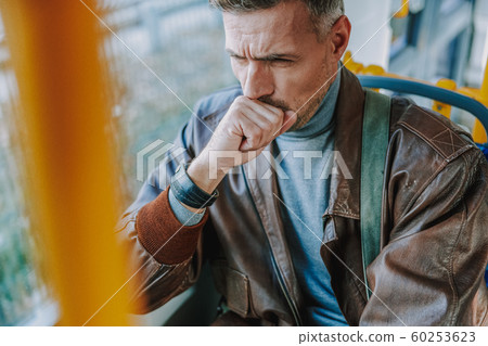 Young man sitting in a tram and coughing 60253623