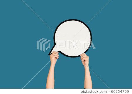 Hands holding the sign of comment on blue studio background 60254709