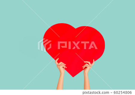 Hands holding the sign of heart on blue studio background 60254806