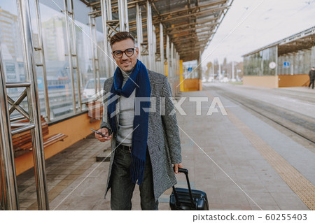 Cheerful handsome man with cellphone walking on the street Cheerful handsome man with cellphone walking on the street 60255403