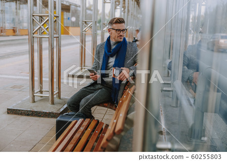 Handsome elegant man sitting on bench outdoors Handsome elegant man sitting on bench outdoors 60255803