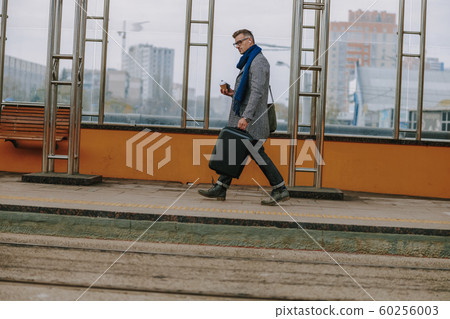 Handsome elegant man walking on the street 60256003