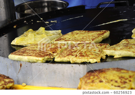 Malaysian street food called Murtabak. Cook by Hawkers. In it there is a mixture of meat, eggs and onions. Eaten with a special gravy. 60256923