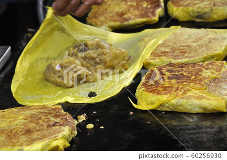Malaysian street food called Murtabak. Cook by Hawkers. In it there is a mixture of meat, eggs and onions. Eaten with a special gravy. 60256930