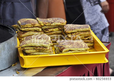 Malaysian street food called Murtabak. Cook by Hawkers. In it there is a mixture of meat, eggs and onions. Eaten with a special gravy. 60256933