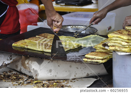 Malaysian street food called Murtabak. Cook by Hawkers. In it there is a mixture of meat, eggs and onions. Eaten with a special gravy. Malaysian street food called Murtabak. Cook by Hawkers. In it there is a mixture of meat, eggs and onions. Eaten with a special gravy. 60256935
